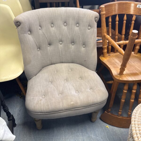 Grey upholstered nursing chair with button back detail.