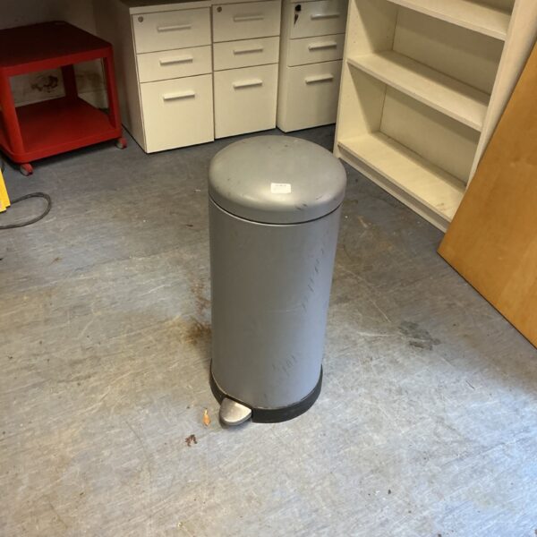 Grey kitchen pedal bin for household waste disposal.