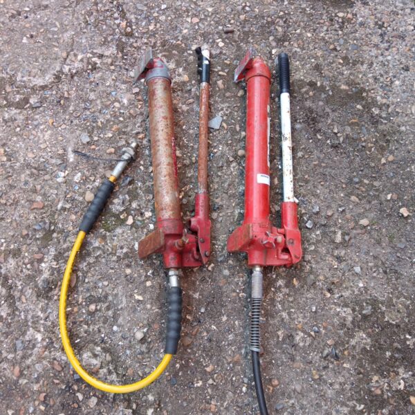 Pair of used hydraulic pumps with flexible hoses.