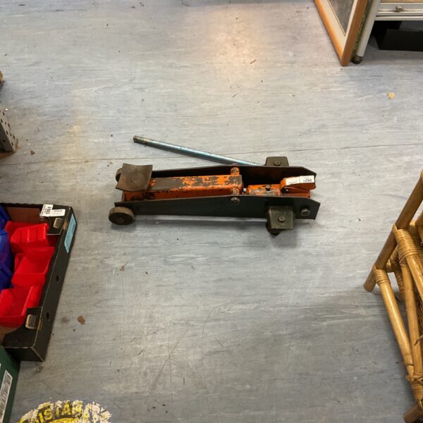 Side view of a used hydraulic trolley jack for car maintenance.