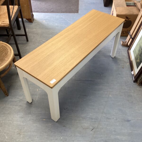 Simple Scandinavian Ikea bench with wooden seat and painted legs.