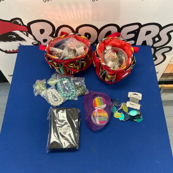 Assorted jewellery making supplies including beads and thread in two bags.