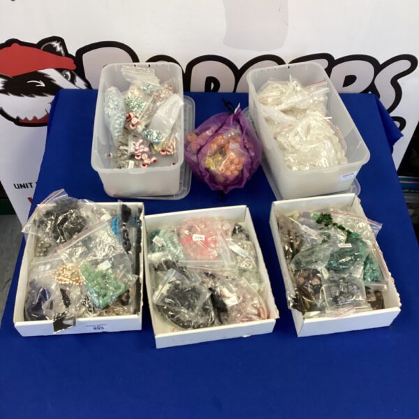 Colorful jewelry making beads and trinkets in plastic boxes.