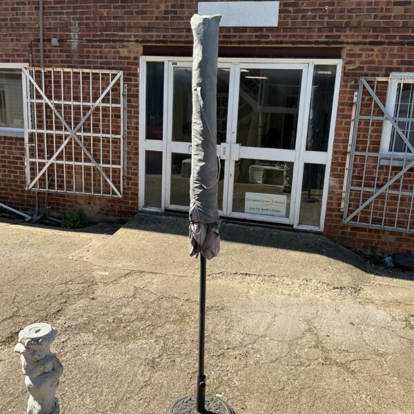 Large garden parasol with stand in outdoor setting.