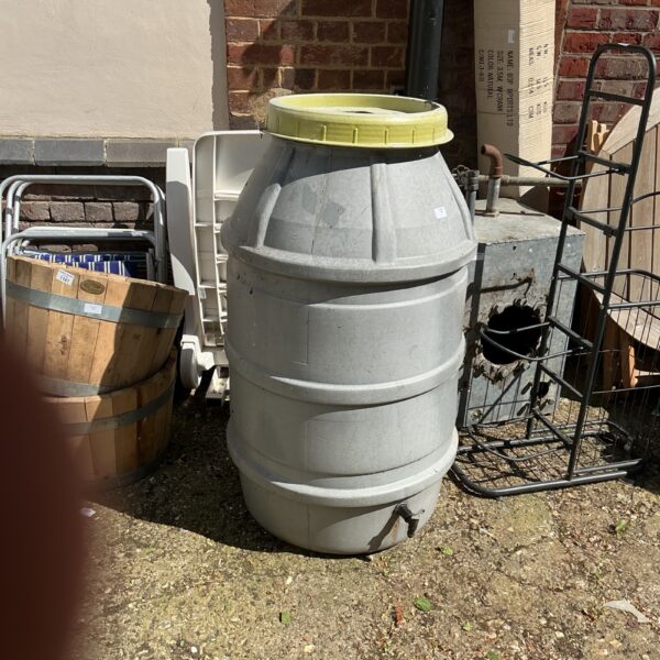 Large plastic water butt for rainwater collection in a garden.