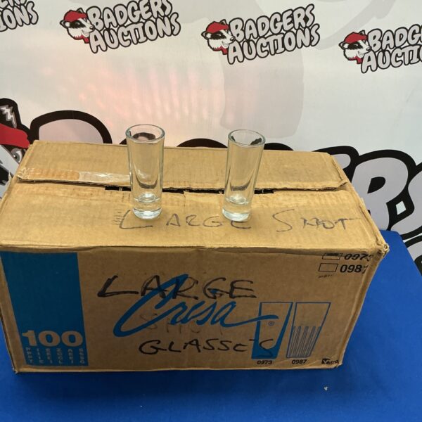 Quantity of large clear shot glasses in a cardboard box.
