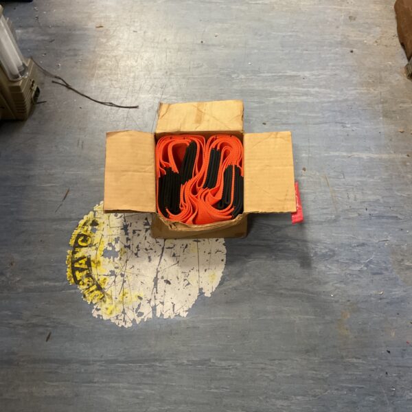 Bright orange lifting slings stacked in a cardboard box.