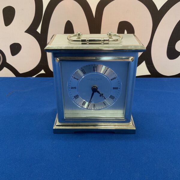 Vintage brass London Clock Company desktop clock on a dark surface.