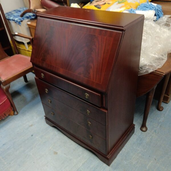 Vintage mahogany writing bureau with drawers, front view.