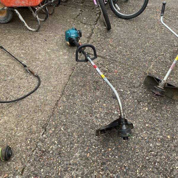 Used Makita petrol strimmer in a garden setting.