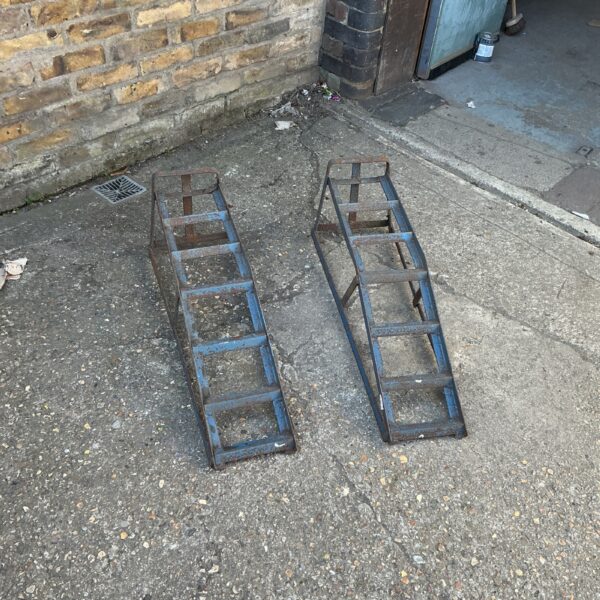 Pair of metal car ramps in a garage setting.
