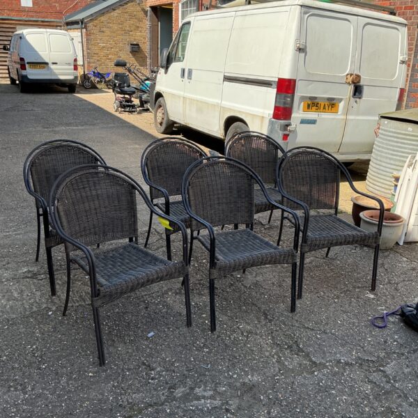 Set of six dark metal garden chairs in a garden setting.
