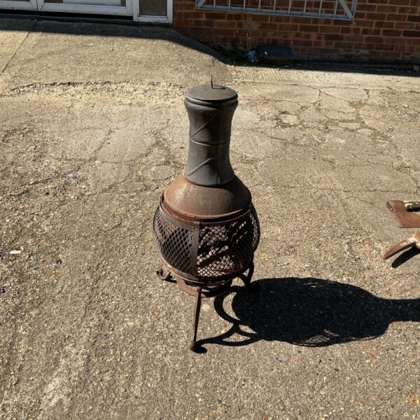 Rustic metal garden chimenea with tripod base for outdoor heating.
