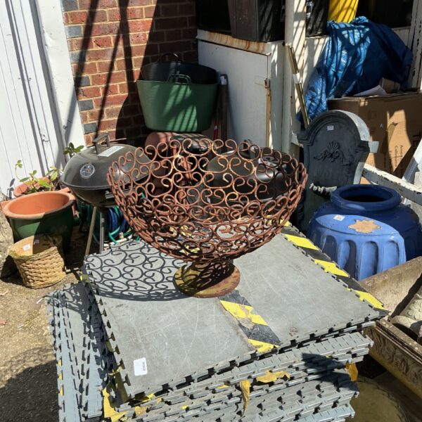 Intricate metal garden plant holder with scrolling design.