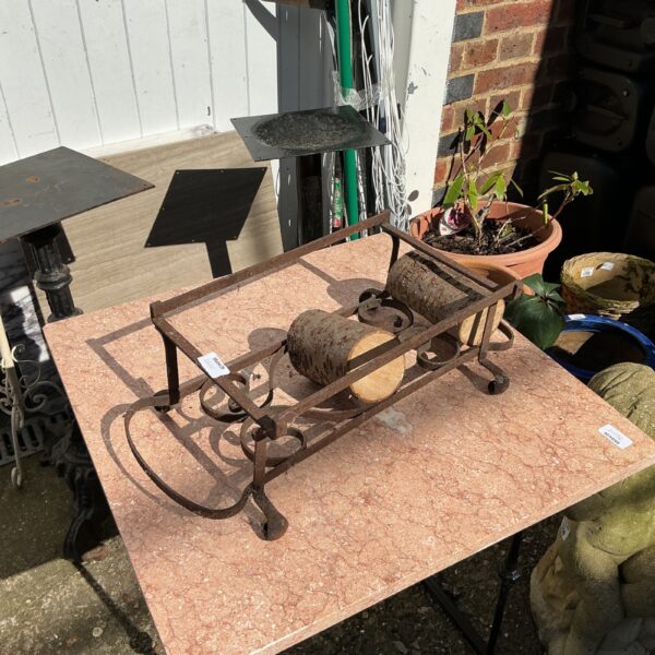 Vintage metal log rack for firewood storage near a fireplace.
