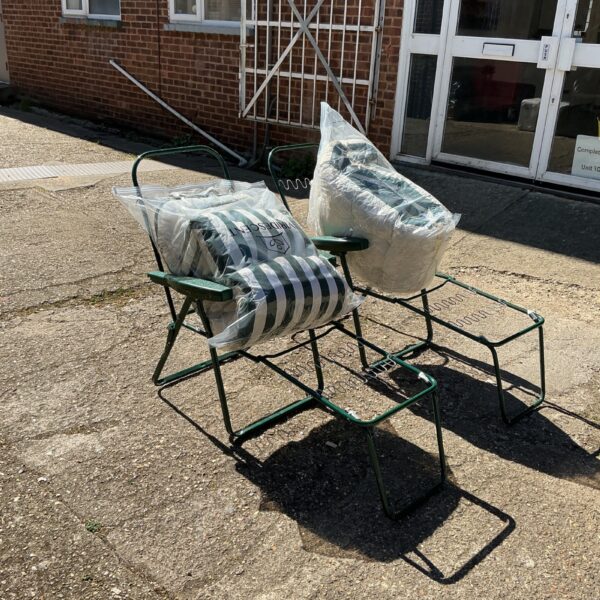 Two metal sun loungers with cushions in a garden setting.