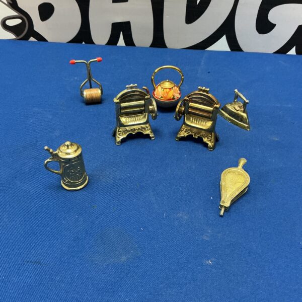 Collection of vintage miniature brass ornaments on a dark surface.