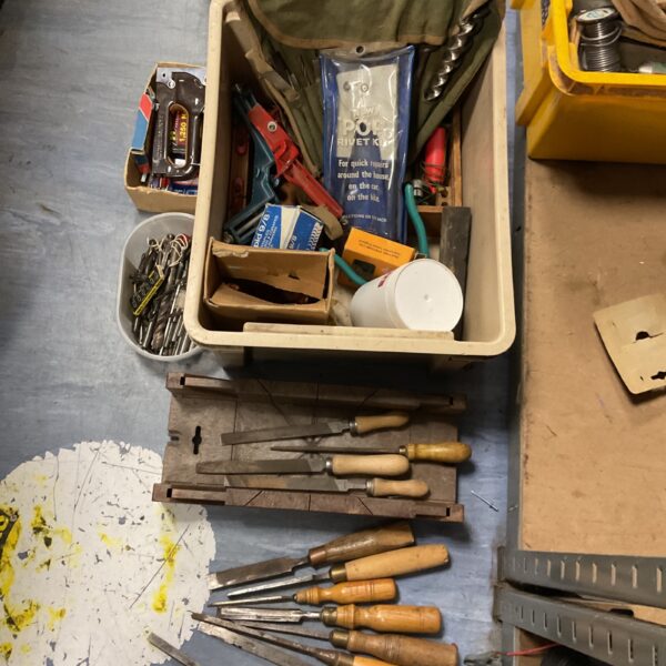 Overview of a mixed tool lot with chisels, drills, and a rivet kit.