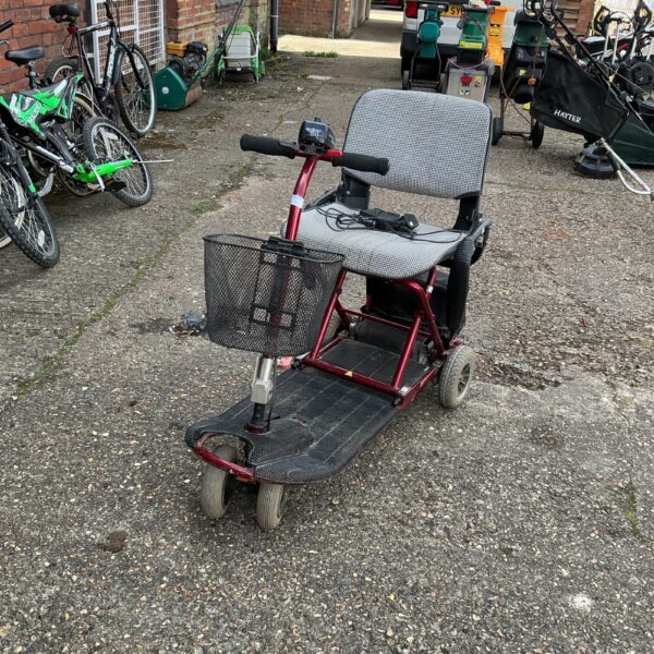 Side view of a portable mobility scooter in a garden setting.