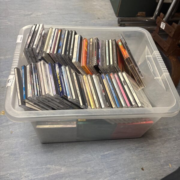 Mixed music CD collection in a plastic storage container.