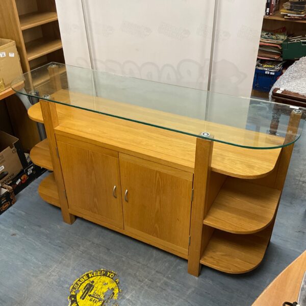 Oak effect console table with glass top and storage shelves.
