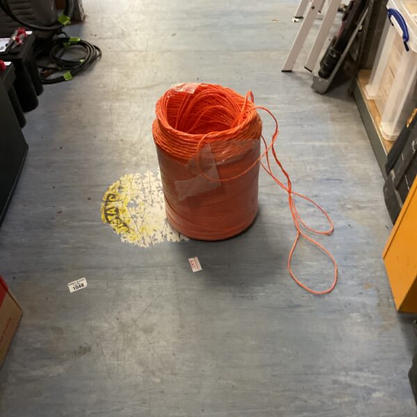 Spool of bright orange nylon trimmer line for garden maintenance.