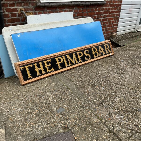 Vintage Pimm’s Bar sign with red lettering and wooden frame.