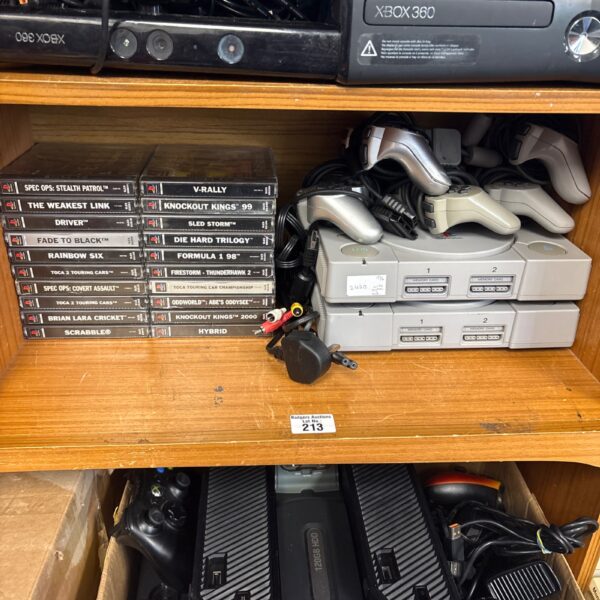 Two Sony PlayStation consoles with games and controllers.