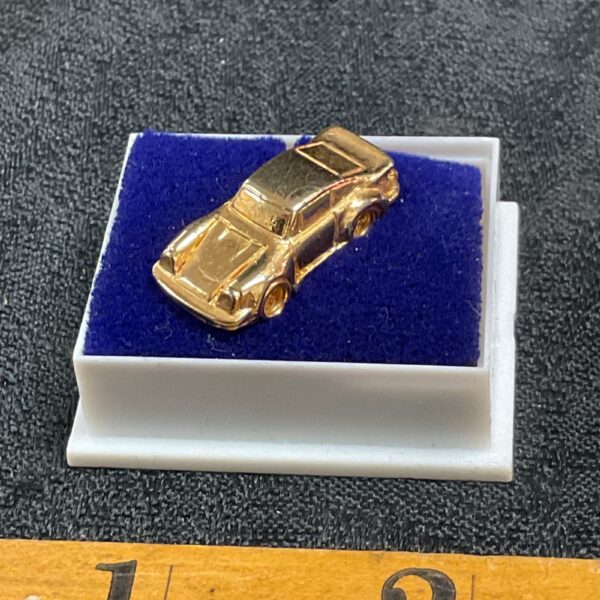 Gilded Porsche 911 pin badge, vintage car collectible.