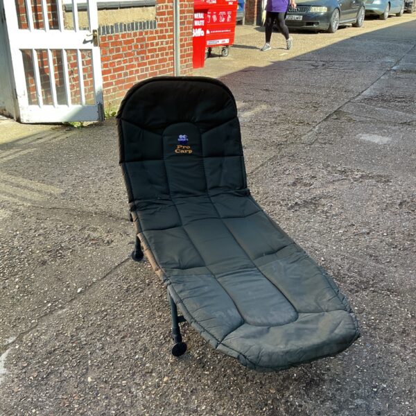 Dark green Pro Carp fishing bedchair angled in a street.