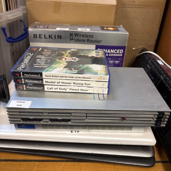 Silver Sony PS2 console with games presented in a lot.