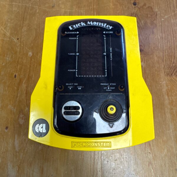 Vintage yellow CGL Puck Monster handheld game, front view.
