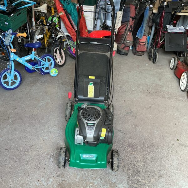 Used Qualcast petrol lawnmower in a garden setting.