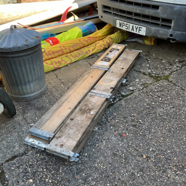 Four weathered wooden raised flower bed boards in a garden setting.