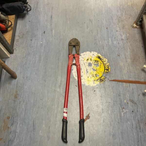 Red bolt cutters for cutting metal, showing signs of wear.