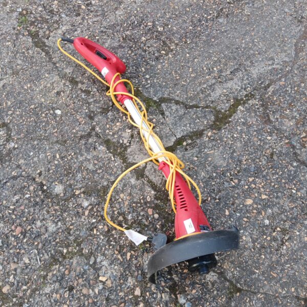 Red electric grass strimmer for garden lawn maintenance.