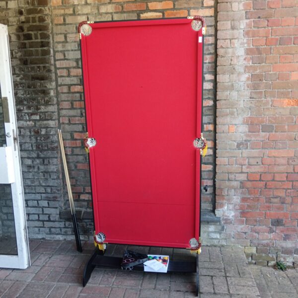 Red folding snooker table with cues and balls for home games.