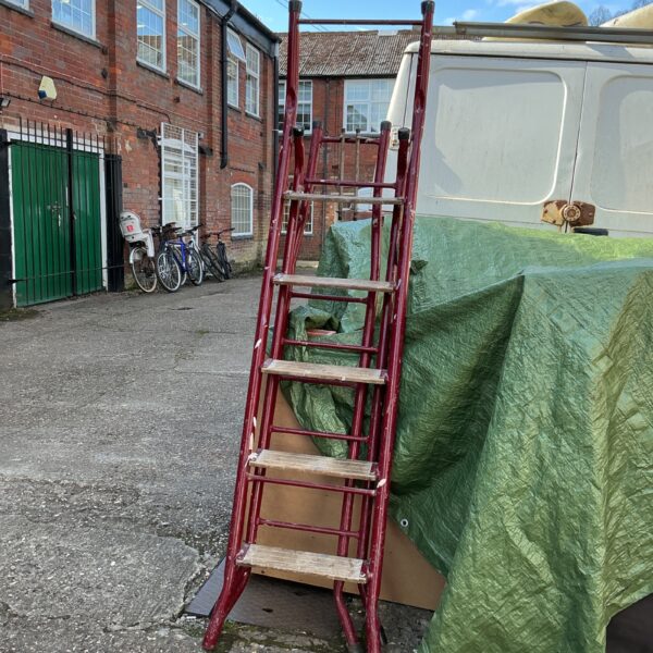 Red metal multi-purpose ladder in a garden setting.