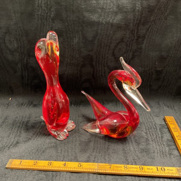Pair of vibrant red Murano style glass ducks on display.