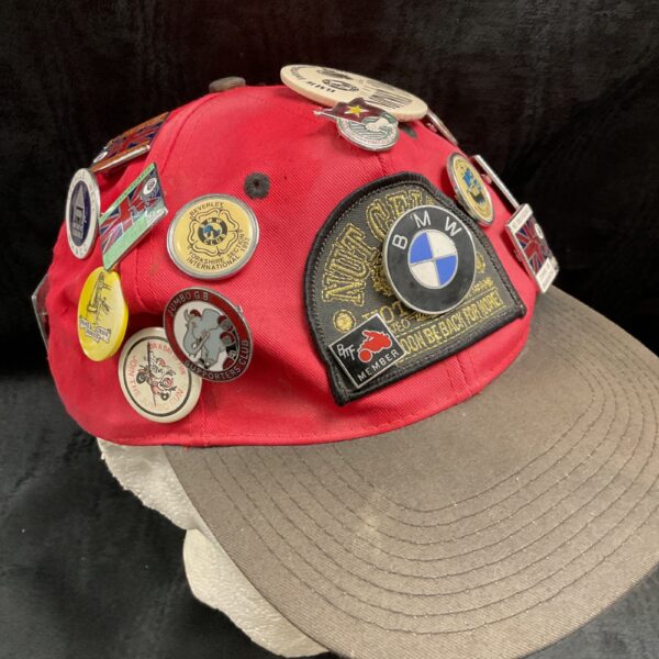 Front view of a red baseball cap covered in pin badges.