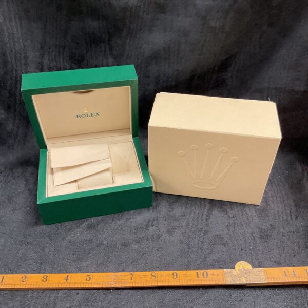 Green Rolex watch box with open lid and white interior.