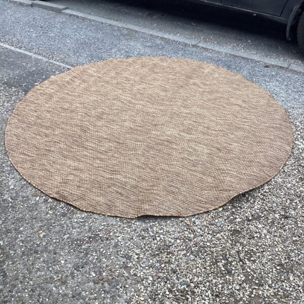 Large round jute rug displayed outdoors on a patio.
