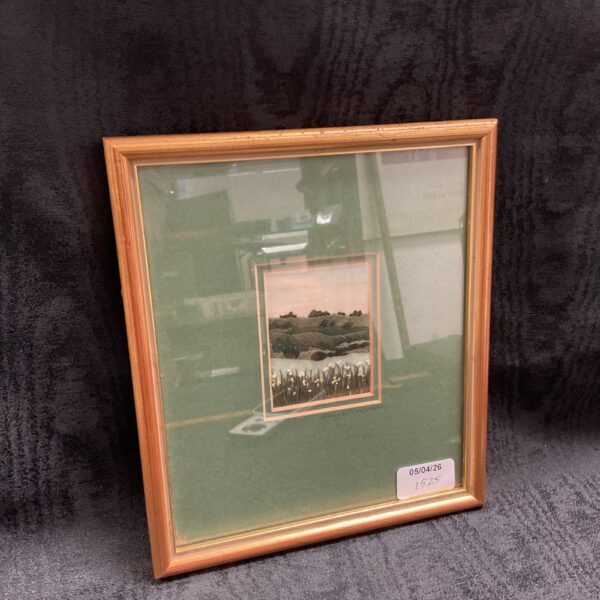 Framed Sally MacCabe embroidery of rolling hills landscape.