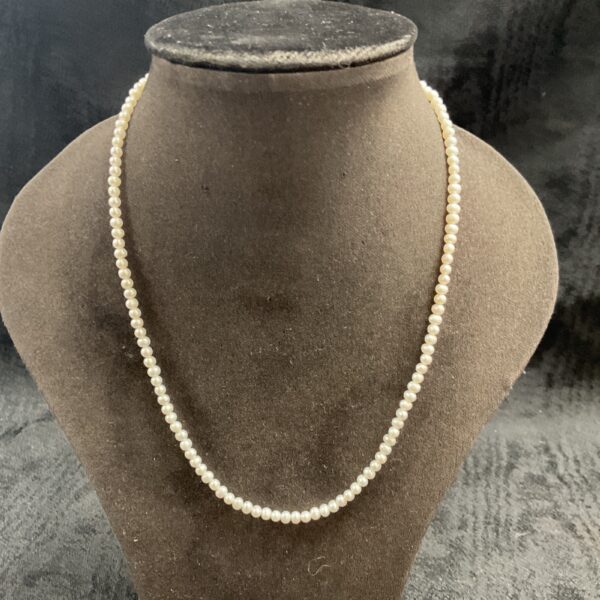 Vintage seed pearl necklace with 9ct gold clasp on display.