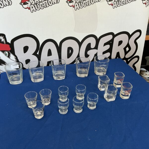 Collection of shot glasses and tumblers including Jack Daniel's branding.