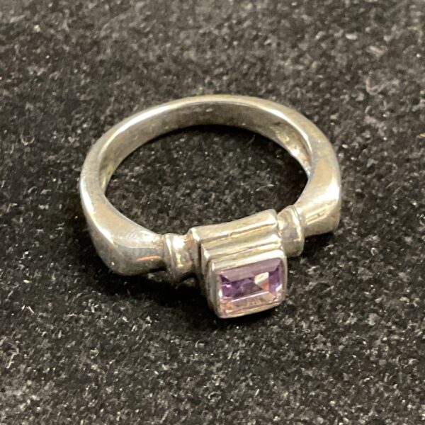 Close-up of a silver ring with a purple amethyst gemstone.