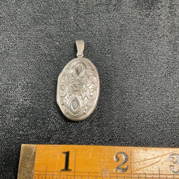 Close-up of a vintage silver Celtic locket with intricate engraving.