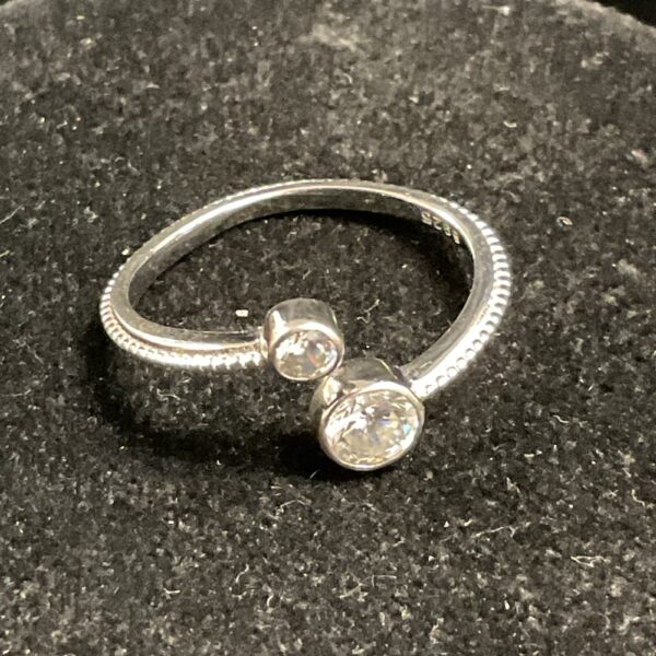 Silver crossover ring with a white stone, size M.