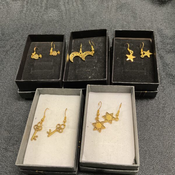 Five pairs of silver gilt earrings on a black display card.