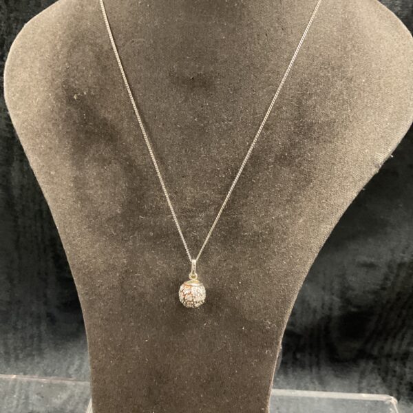 Silver glitterball pendant necklace on a display.